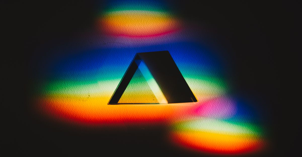 Colorful dispersion of light through a prism creating a vibrant rainbow spectrum on a dark background.